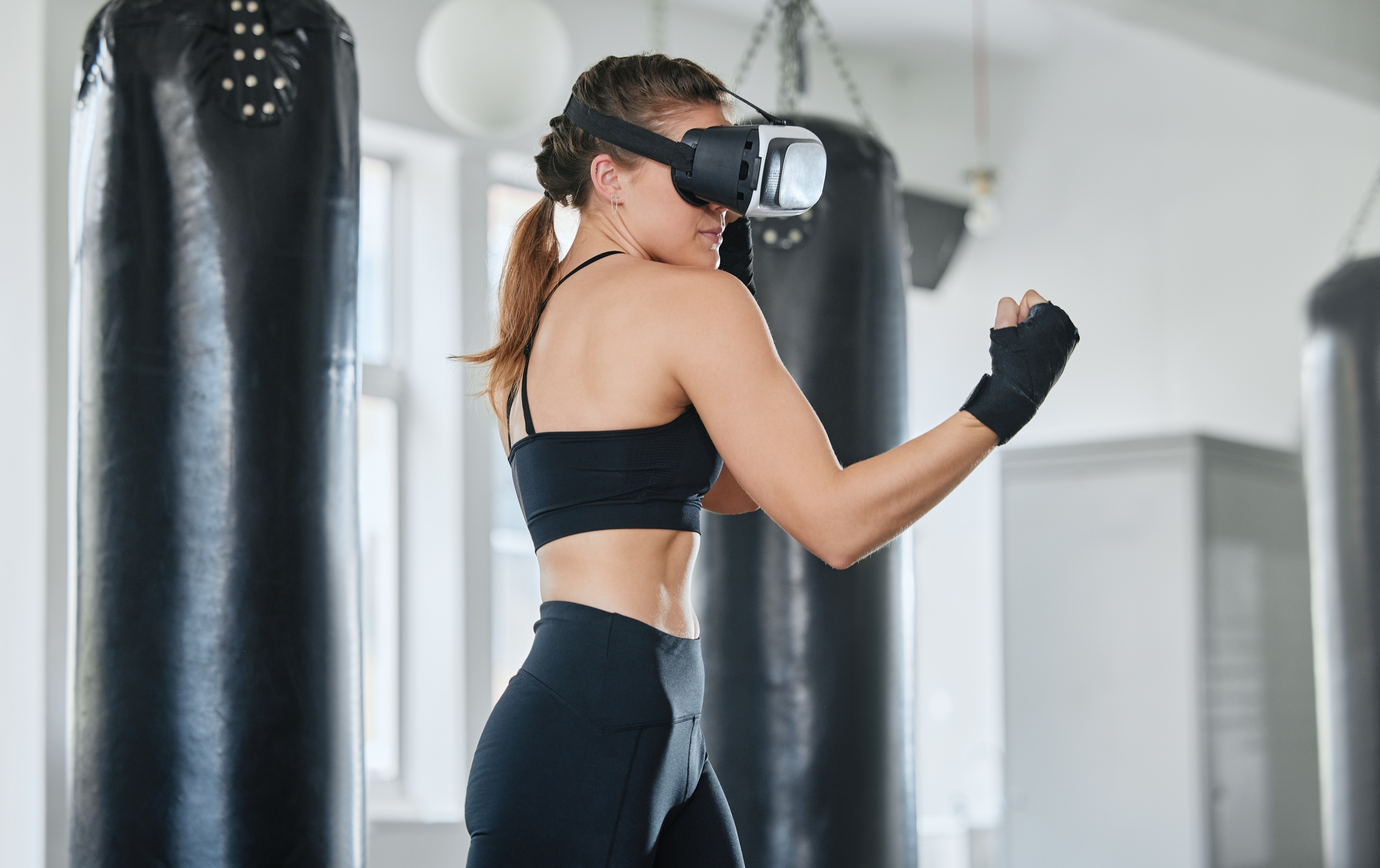 Female boxer using VR goggles to train, exercise and stay fit and healthy in a modern fitness gym.